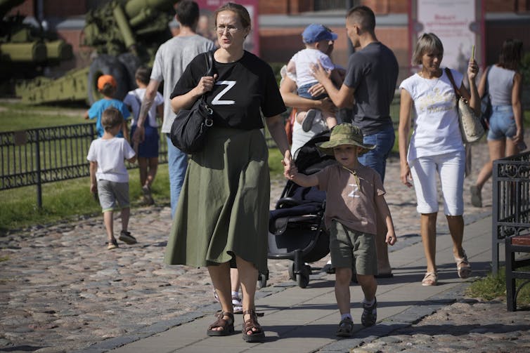 A woman and child walk along a street with T-shirts with the letter Z on them.