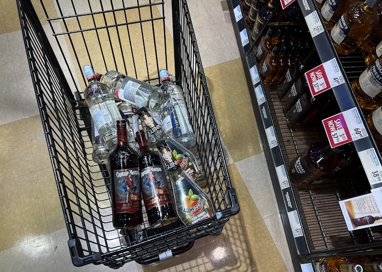 A shopping cart with several bottles of liquor in it