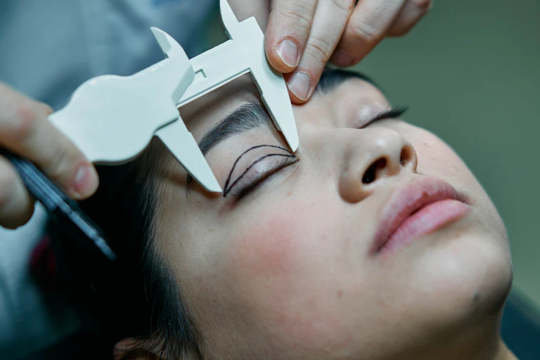 Cosmetic surgeon measuring eyelids ahead of surgery