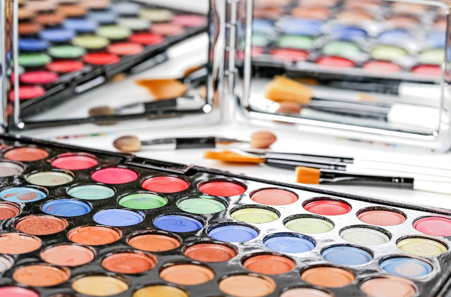 Trays of makeup in front of a mirror