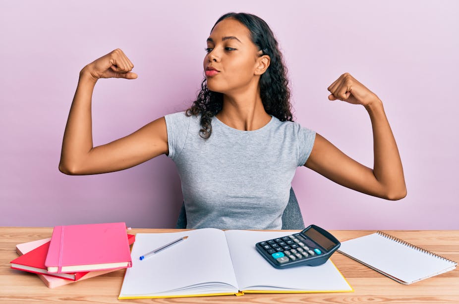 Woman with calculator next to her showing arms muscles smiling proud
