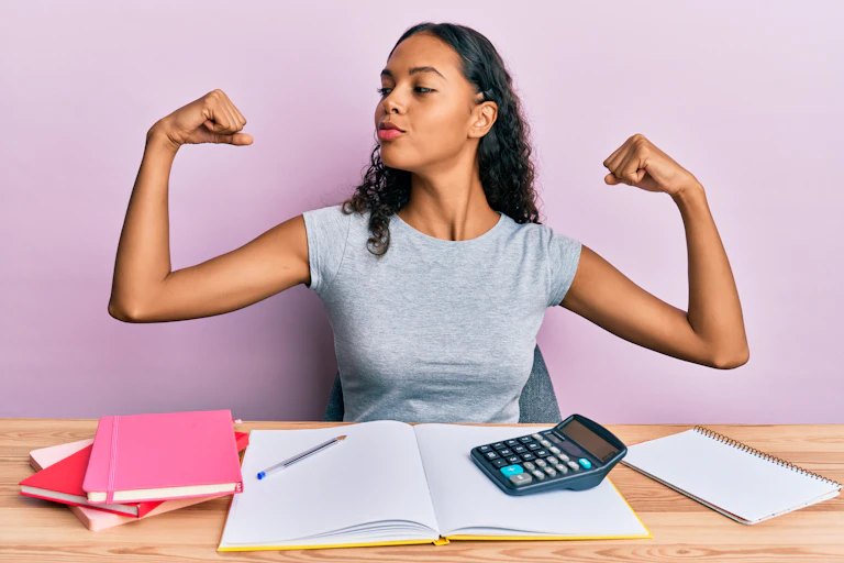 Woman with calculator next to her showing arms muscles smiling proud