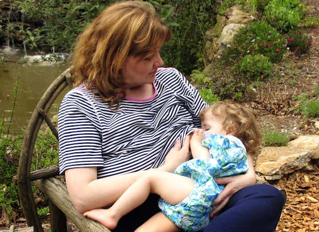 Woman breastfeeding baby in park