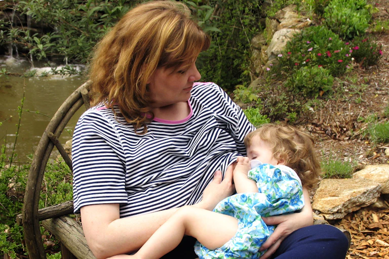 Woman breastfeeding baby in park