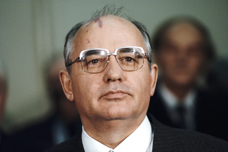 Mikhail Gorbachev in steel-rimmed glasses looks into the distance