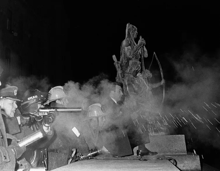 A statue of an Indigenous chief is seen amid clouds of tear gas during a violent protest.
