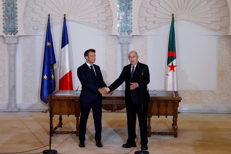Emmanuel Macron et Abdelmadjid Tebboune se serrant la main lors d'une cérémonie à Alger.