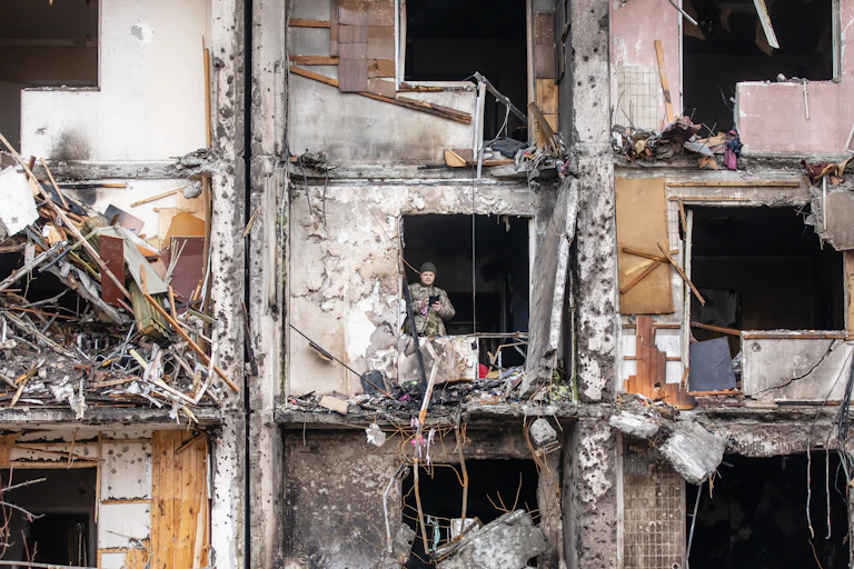 A Ukrainian soldier is standing in a building that was destroyed by Russian artillery attacks.
