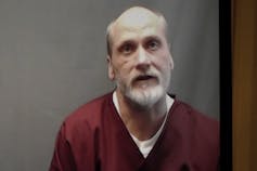 A video screen shows death row inmate James Coddington dressed in prison clothes.