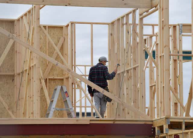 Man works on timber building frame