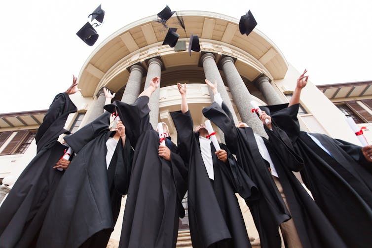 Graduates in robes throwing mortarboards in the air