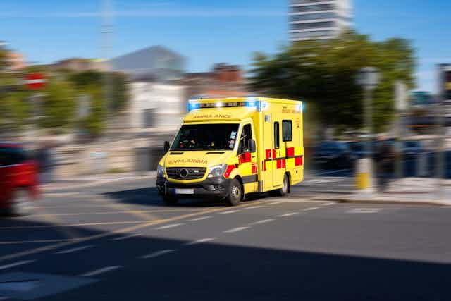 An ambulance driving. The background is blurred.