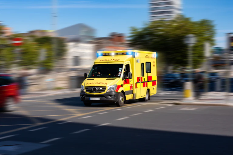 An ambulance driving. The background is blurred.