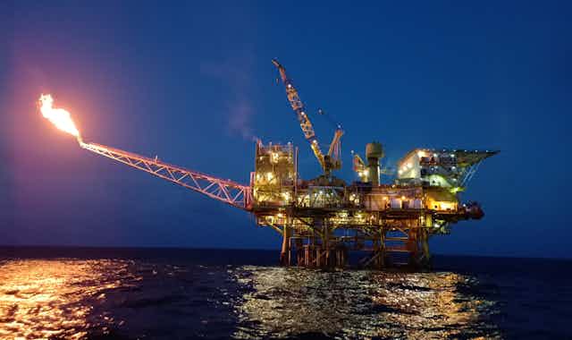 A drilling platform with a lit gas flare.