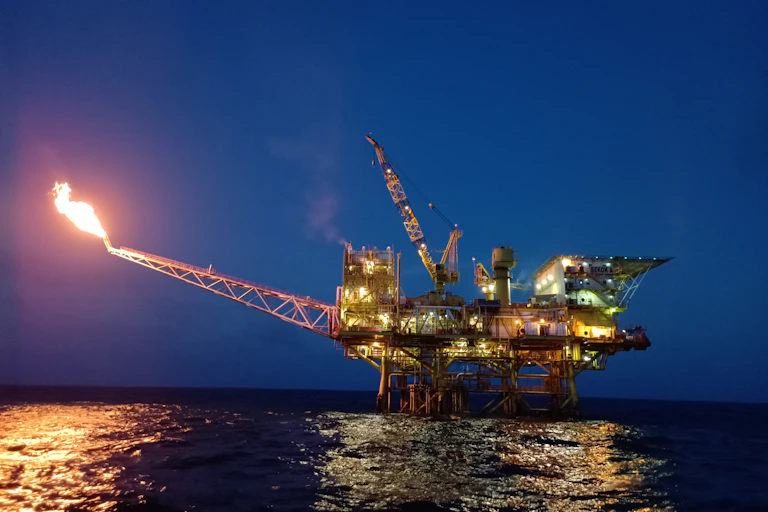 A drilling platform with a lit gas flare.