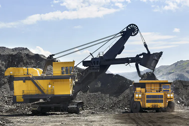 An excavator loads coal onto a truck.