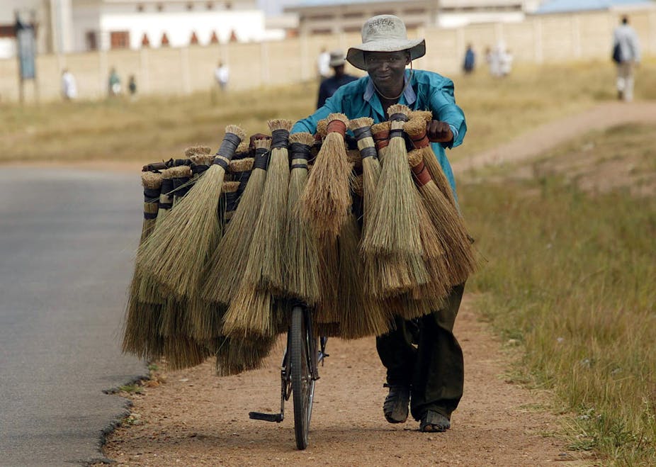 A Zimbabwean broom vender pushes his bike on the streets of Chitungwiza outside Harare