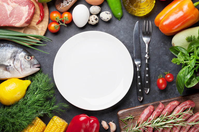 Une assiette blanche est entourée de produits crus susceptibles d'être contaminés : poisson, viande, œufs, légumes…