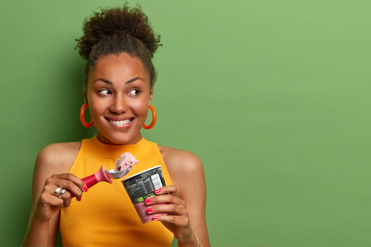 Curly haired woman holds a scoop of ice cream