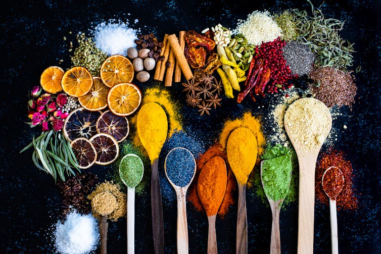 Many multi coloured spices and dried fruits on a black table