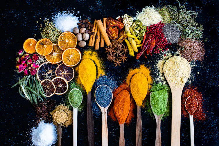 Many multi coloured spices and dried fruits on a black table