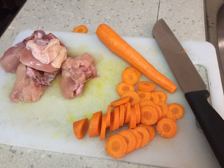 Planche à découper où sont mélangés viande et légumes
