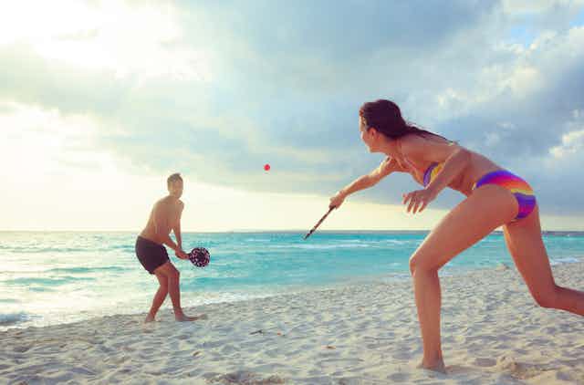 Peaceful beach landscape with young, fit couple playing a beach tennis game