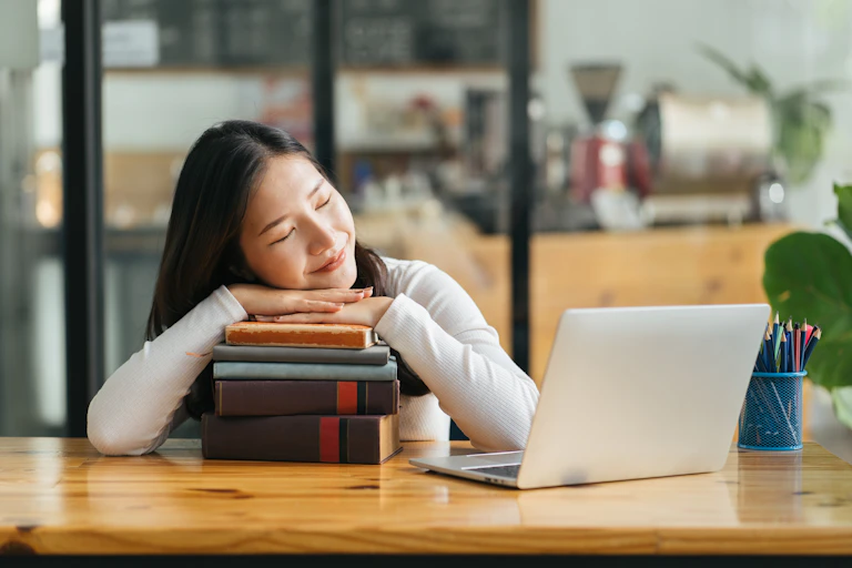 Jeune fille dormant sur une pile de livres.