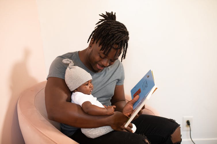 A dad seen reading to his baby.