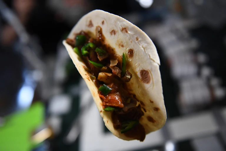 A taco floating in air, filled with red and green veggies