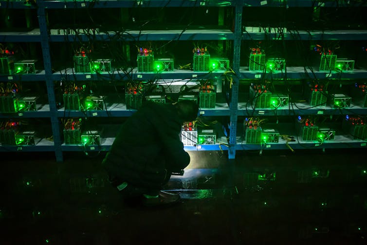 green-lit computers in darkened room with person tinkering