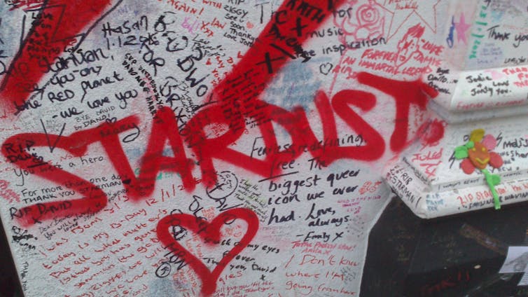 Dedicatorias escritas sobre un muro con la palabra Stardust en rojo y grandes letras sobre ellas.