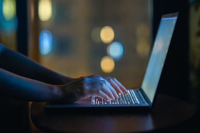 Hands can be seen typing on a laptop. on a laptop