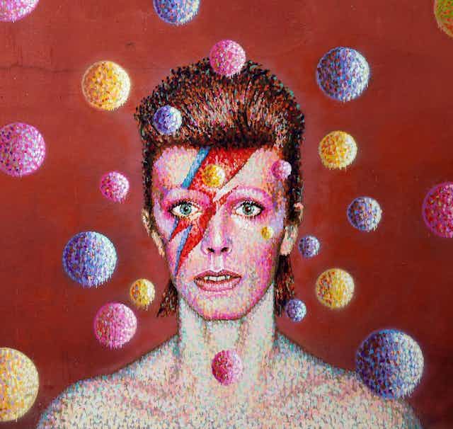 Retrato mural de David Bowie como Ziggy Stardust rodeado de esferas de colores sobre fondo rojo.