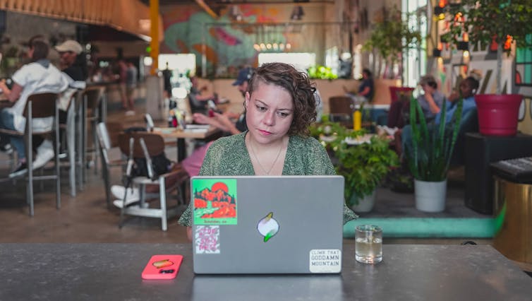 Seorang perempuan dengan laptopnya di kafe berinternet