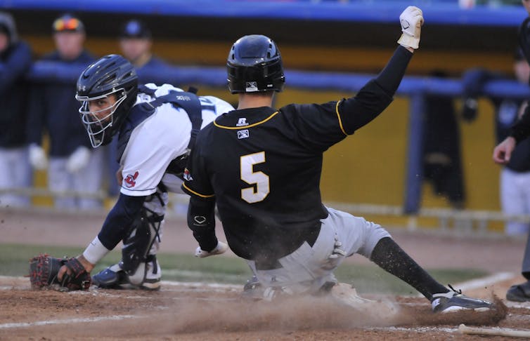 Baseball player slides into home plate to avoid a tag.