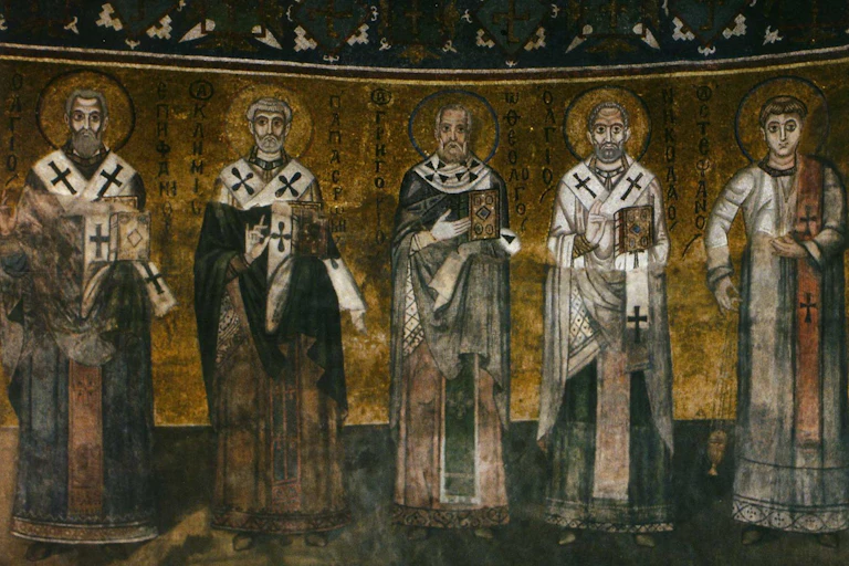 A dark and gold mosaic shows five men in robes with halos around their heads.