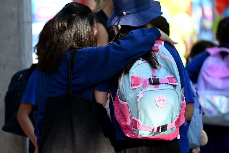 School students put their arms over each other.