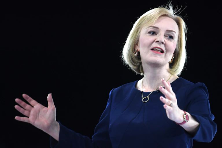A woman displays an open arms gestures as she addresses an audience.