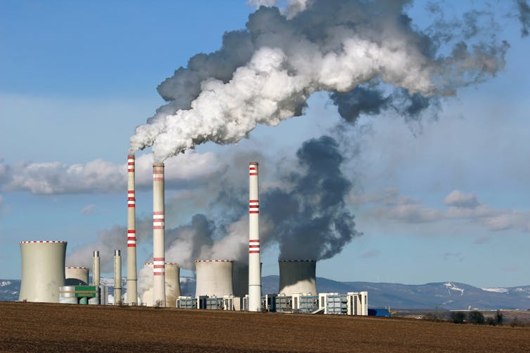 A coal-fired power station with fumes pouring into a blue sky.