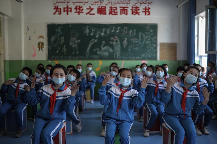 Schoolchildren gesture as they sing a song during their class at a primary school in Awati Township in Kashgar in western China's Xinjiang Uyghur Autonomous Region