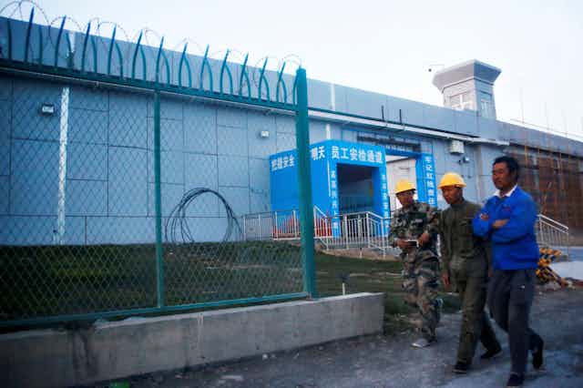 Workers walk by the perimeter fence of what is officially known as a vocational skills education centre in Dabancheng in Xinjiang Uighur Autonomous Region, China September 4, 2018.