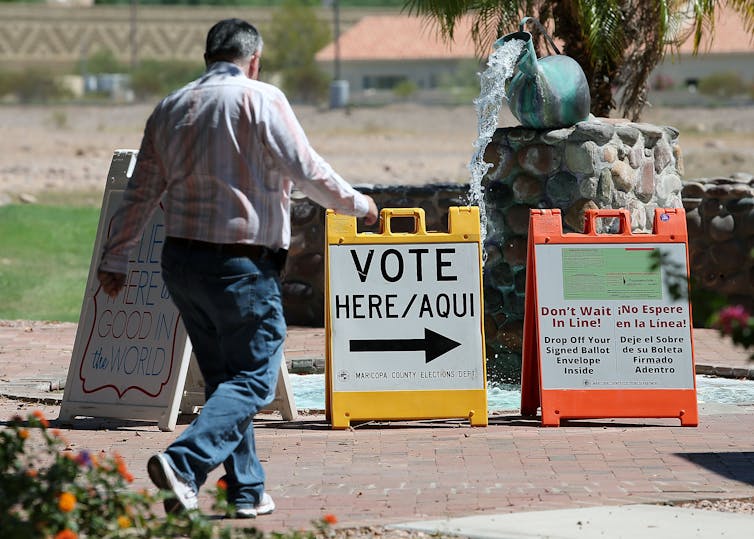 As in many other states, a voter is walking by Election Day signs that are written in English and Spanish.