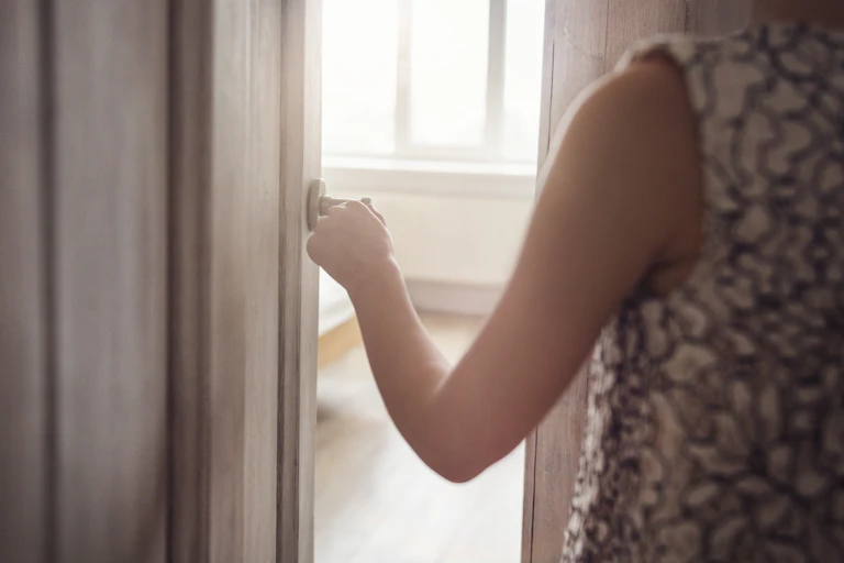 arm on door handle opening door to room