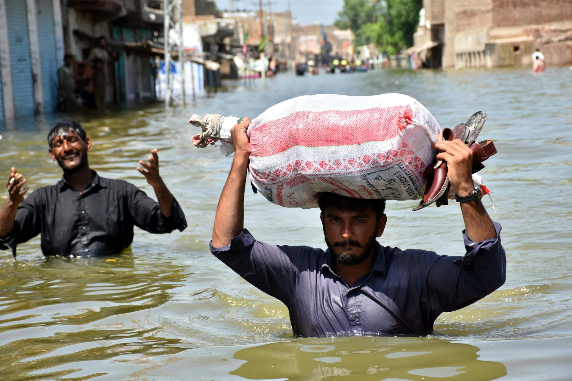 Two men wade through chest-high water.