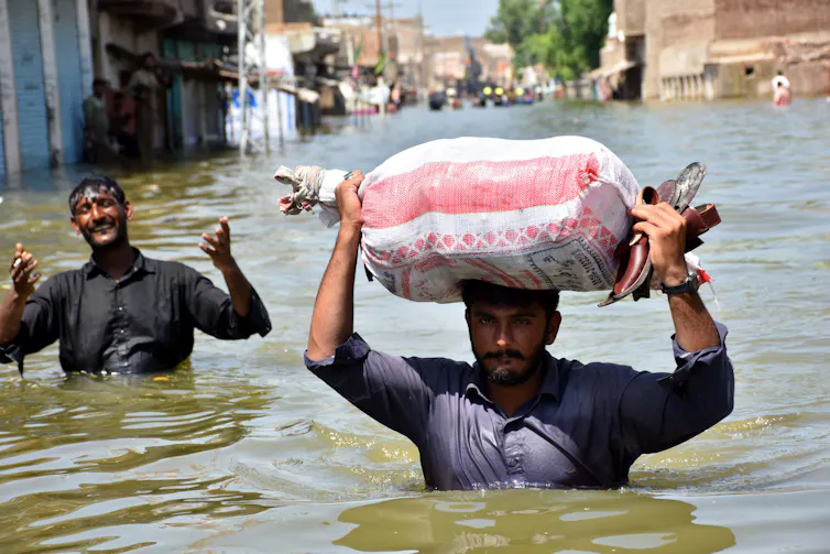 Two men wade through chest-high water.
