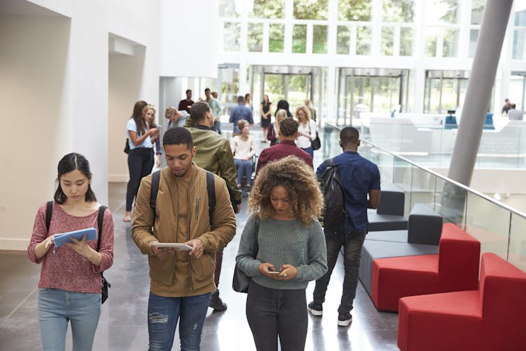 Post-secondary students seen walking in a corridor.