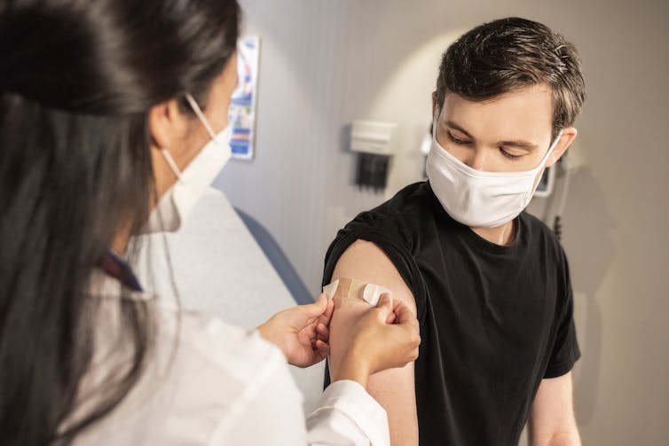 A young man has a plaster put on after he has received a vaccination.
