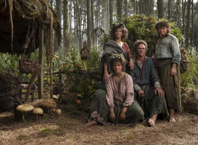 Four actors dressed as hobbits in a forest. 