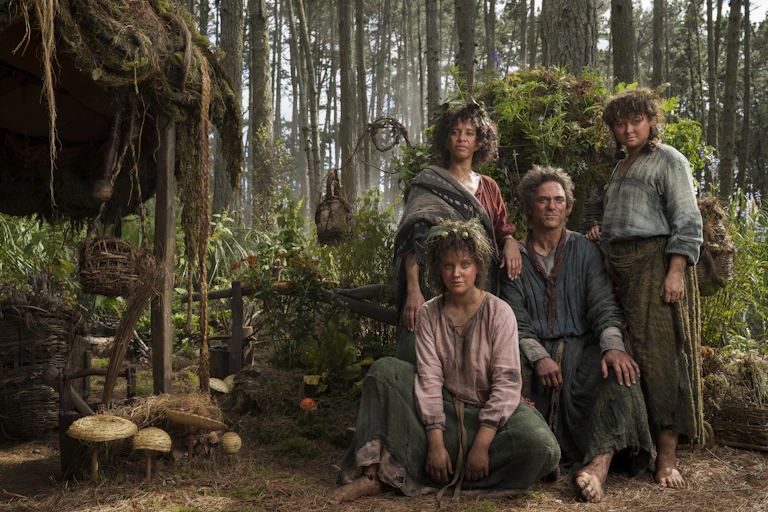 Four actors dressed as hobbits in a forest.